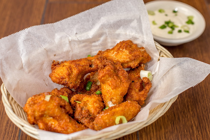 Crispy fried chicken wings in basket with dipping sauce