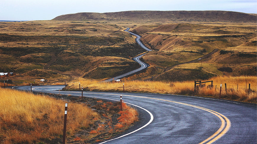 Winding asphalt road through golden autumn hills
