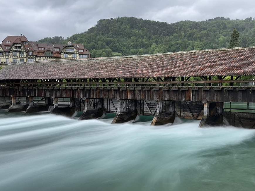 Long exposure of historic covered wooden bridge over rushing river