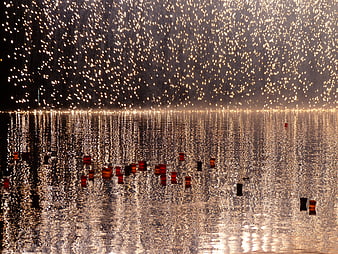 Floating candles on water with silver rain sparks background