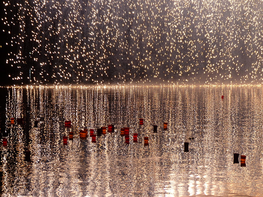Floating candles on water with silver rain sparks background