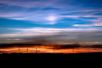Silhouetted Wind Turbines Against Vibrant Sunset Sky