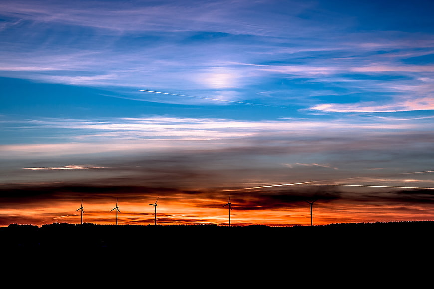 Silhouetted Wind Turbines Against Vibrant Sunset Sky
