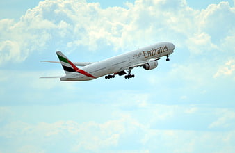 Emirates Airplane Taking Off Against Blue Sky with Clouds
