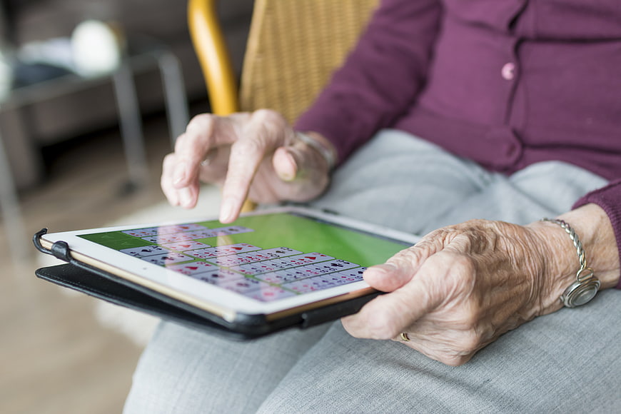Senior woman playing digital card game on tablet