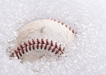 Worn baseball ball resting in fresh white snow