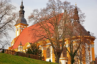 Historic Baroque Monastery Church With Red Roof And Bare Trees