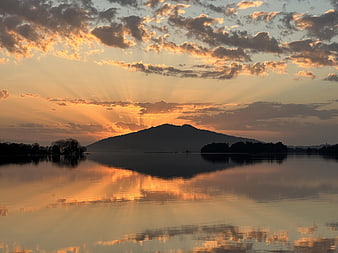 Dramatic Sunset Over Mountain Lake with Sun Rays and Reflection