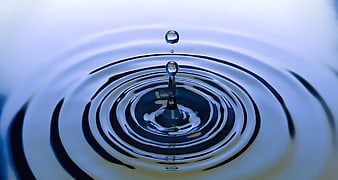 Macro water drop splash with ripples on blue surface