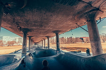 Skateboarders at Urban Concrete Skatepark Under Highway