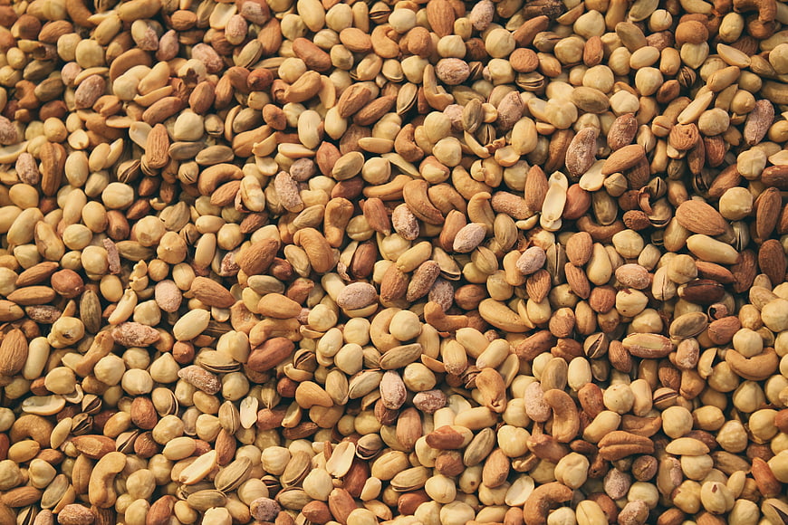 Close-up texture of mixed raw nuts including almonds, cashews, and pistachios