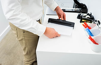 Man using paper punch in modern office workspace