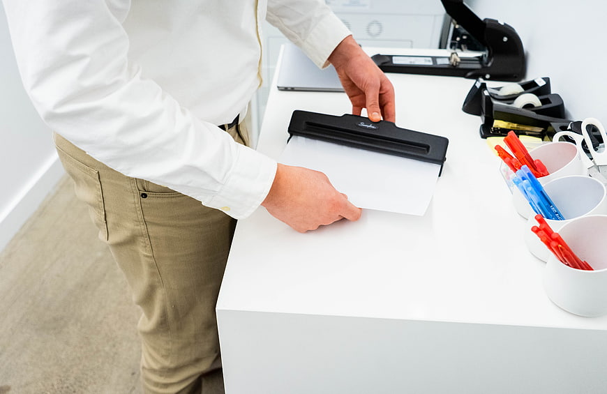 Man using paper punch in modern office workspace