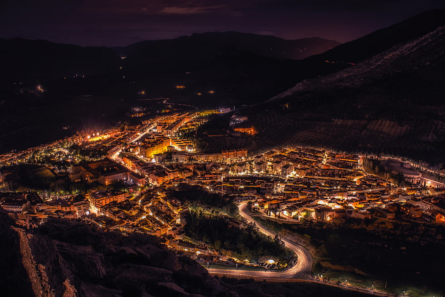 Aerial night view of illuminated mountain town nestled in valley
