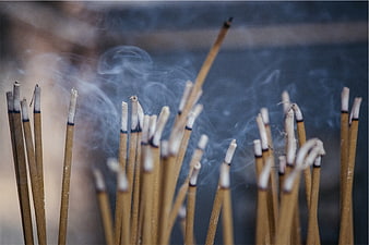 Close-up of burning incense sticks with swirling smoke