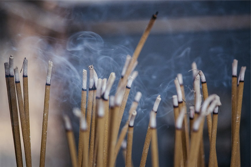 Close-up of burning incense sticks with swirling smoke