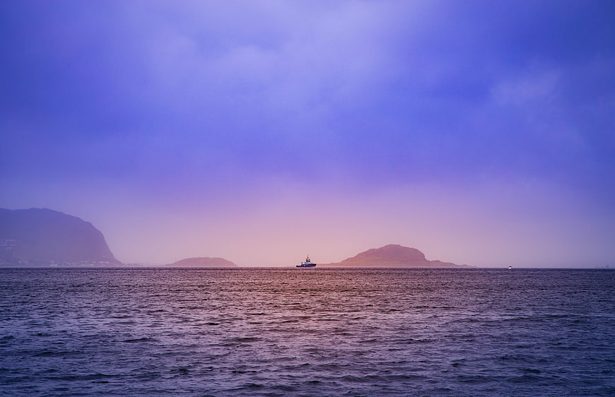 Serene Purple Sunset Seascape with Distant Boat and Islands