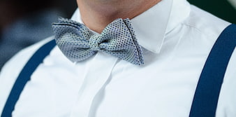 Close-up of man in white shirt with blue suspenders and polka dot bowtie