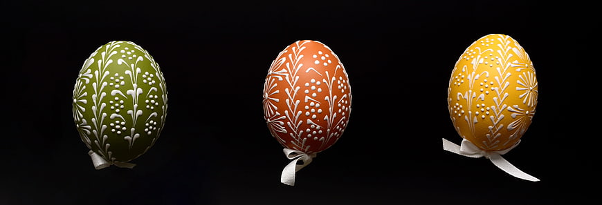 Three Decorated Easter Eggs With White Floral Patterns On Black Background