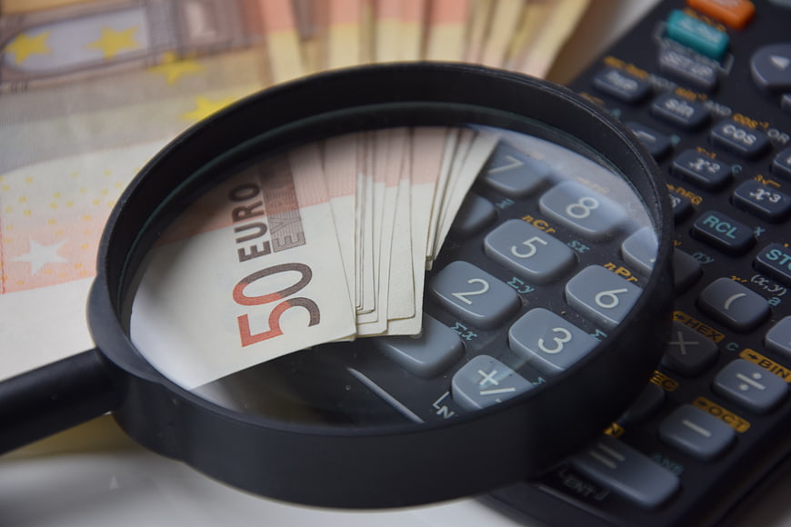 Magnifying glass over 50 Euro banknotes and calculator