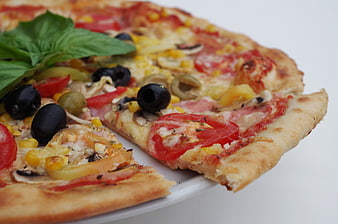 Close-up of a freshly baked vegetable pizza with olives and basil