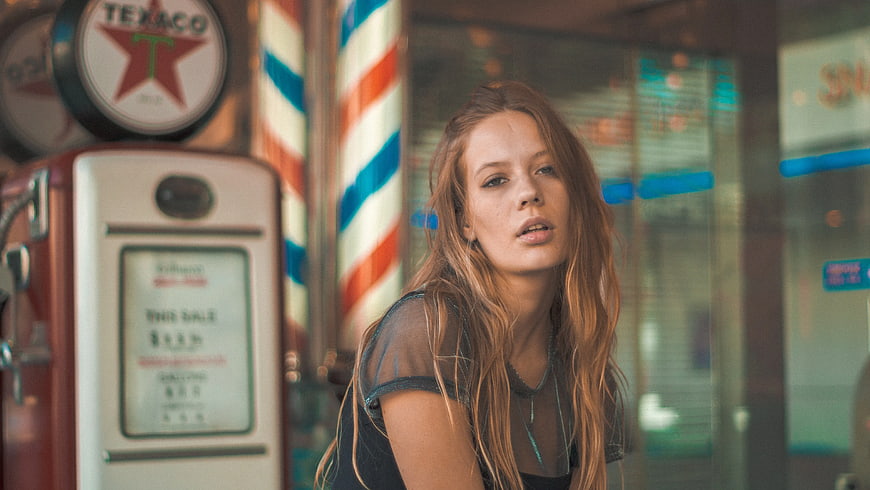 Young Woman with Vintage Gas Pump and Barber Pole