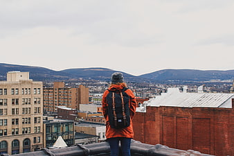 Woman with backpack on rooftop overlooking city and mountains