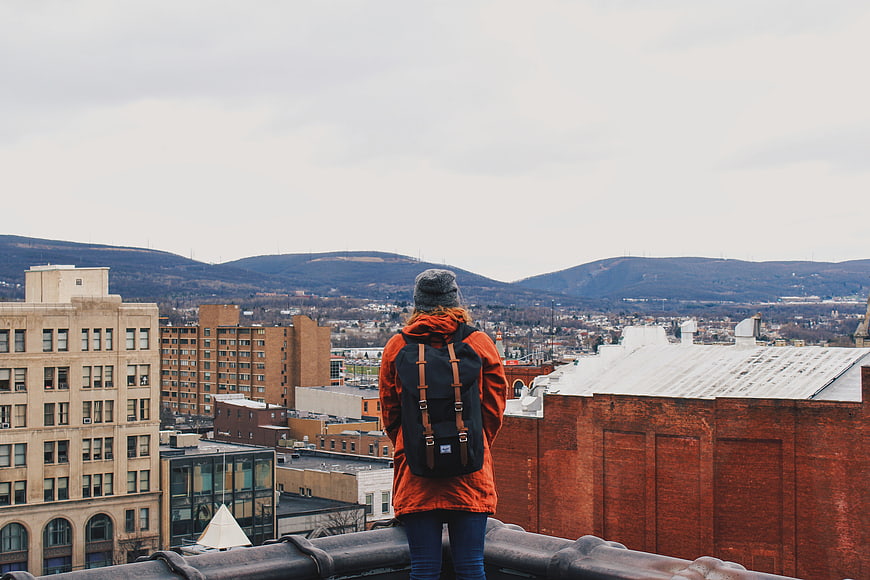 Woman with backpack on rooftop overlooking city and mountains