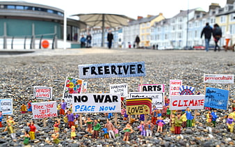 Miniature figurines holding protest signs on a pebble beach