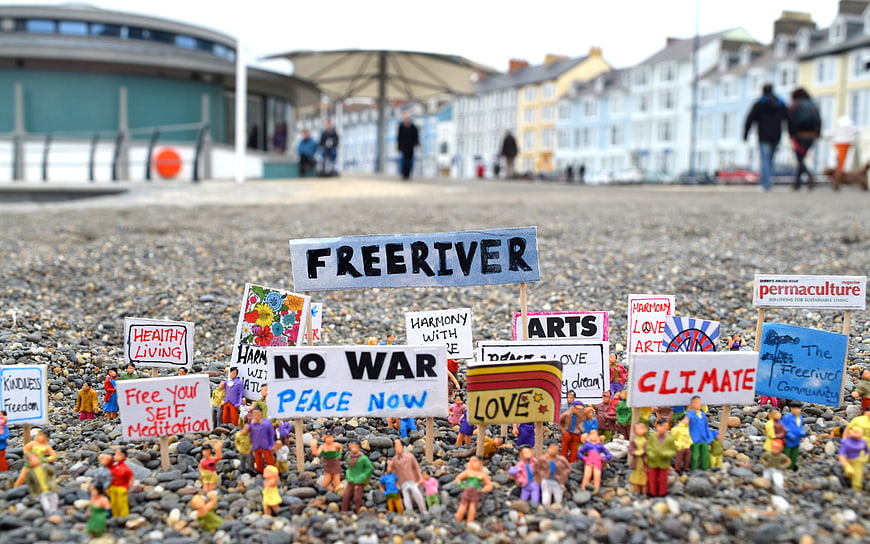 Miniature figurines holding protest signs on a pebble beach