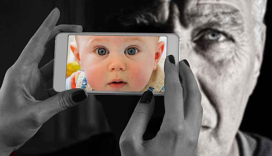 Senior man holding smartphone with baby photo on screen