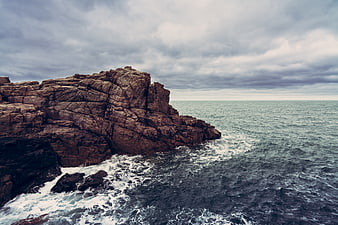 Dramatic Rocky Coastline with Crashing Waves and Cloudy Sky
