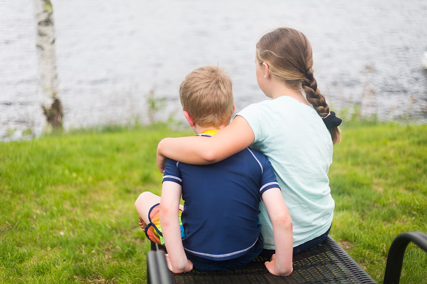 Brother and Sister Sitting on Bench by Lake