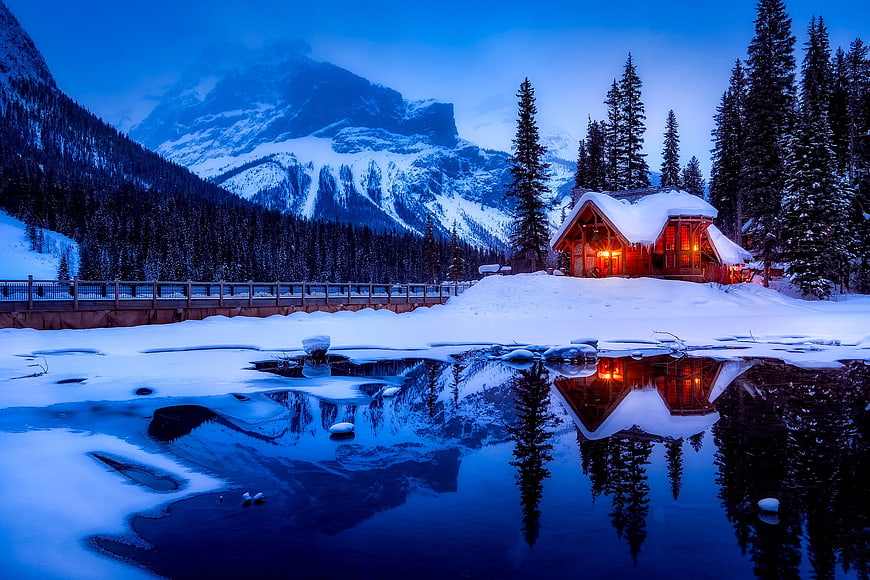 Cozy Log Cabin with Warm Lights Reflected in Frozen Lake at Dusk