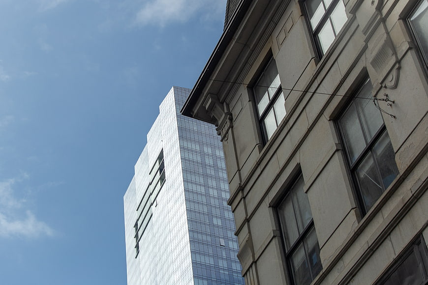 Contrast Between Modern Glass Skyscraper and Historic Stone Architecture