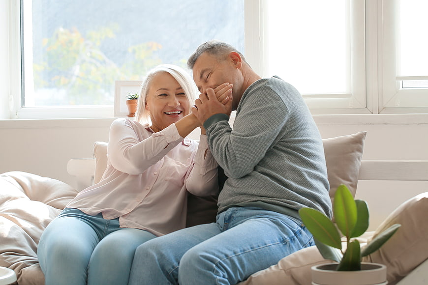 Happy Senior Couple Laughing Together on Sofa at Home
