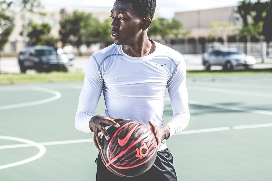 Young male athlete holding basketball on outdoor court