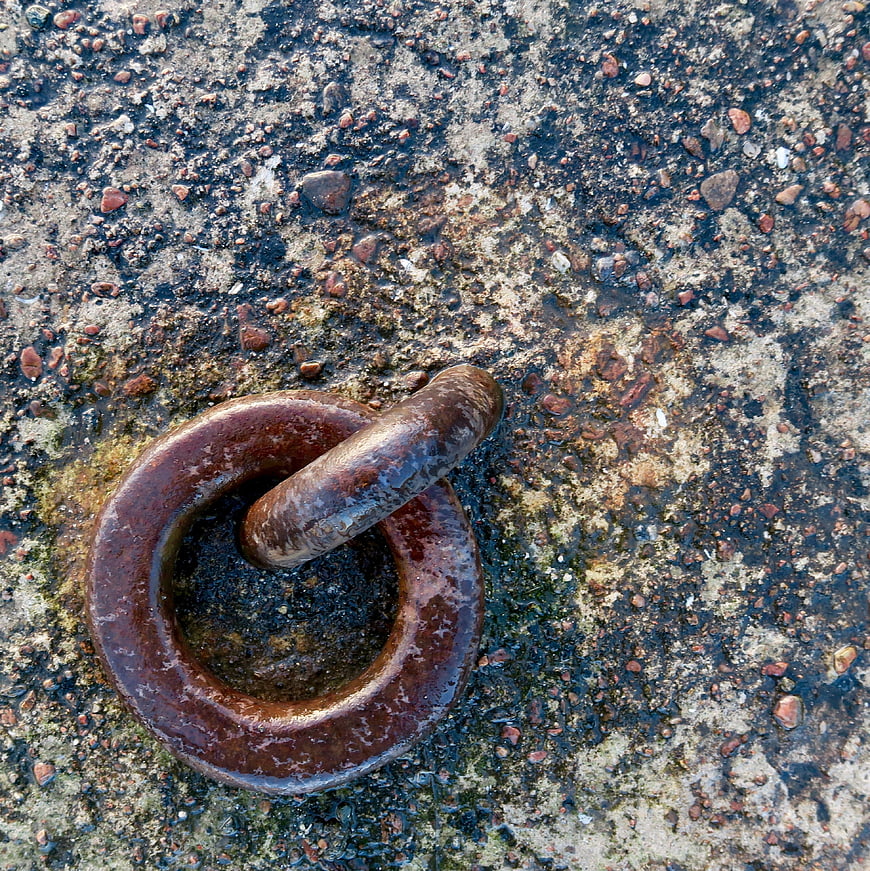 Rusty metal ring on wet concrete texture background