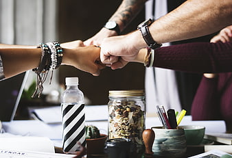 Team Fist Bump Over Cluttered Office Desk