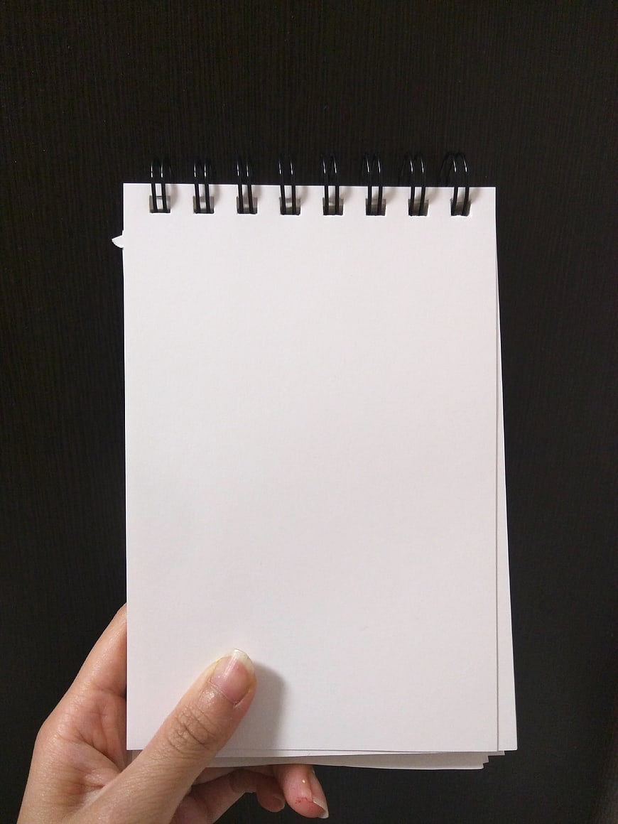 Hand holding blank spiral notebook on dark background