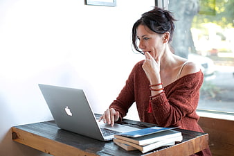 Woman working on laptop at wooden table in bright cafe