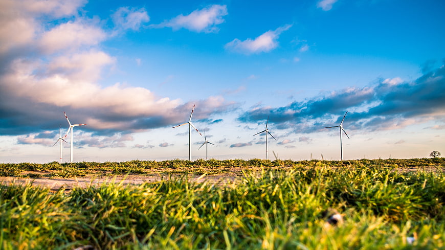 Wind turbines in green field under blue sky