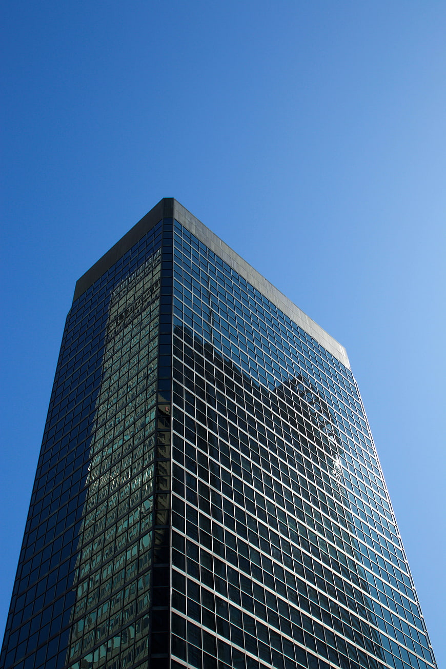 Low angle view of modern glass skyscraper against blue sky