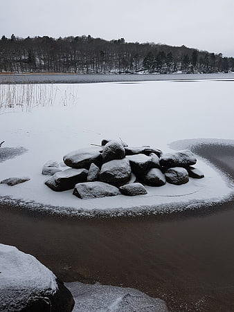 Snow-covered rocks on frozen lake shore in winter