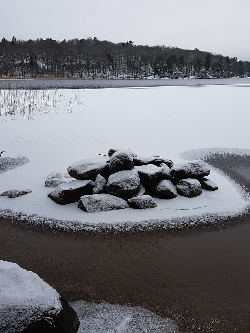 Snow-covered rocks on frozen lake shore in winter