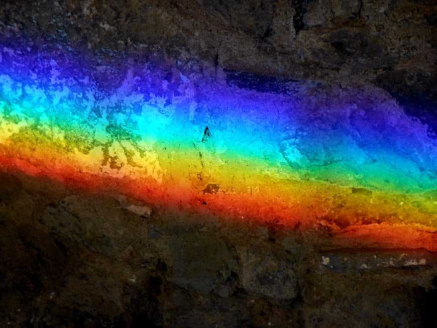 Vibrant rainbow light projection on textured stone wall