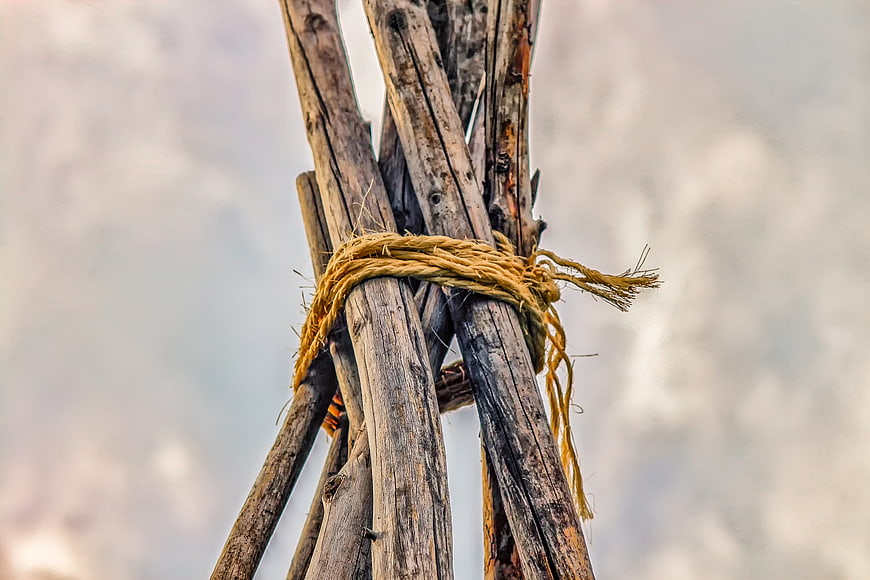 Weathered wooden poles tied with yellow rope against a blurred background