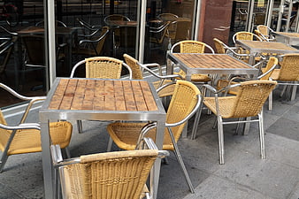 Empty outdoor cafe seating with wicker chairs and wooden tables