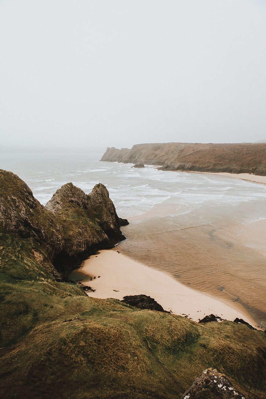 Misty coastal cliffs and sandy beach landscape view
