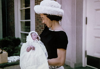 Vintage photo of mother holding yawning baby in white bonnet
